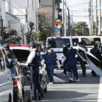 Investigators are seen Tuesday near an apartment in Suginami Ward, Tokyo, where a woman was found stabbed in the back earlier in the day. | KYODO