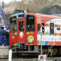 Local students welcome a Sanriku Railway Co. train decorated with a design they helped make at Unosumai Station in Kamaishi, Iwate Prefecture, on Sunday, when regular train services resumed on the Rias Line. | KYODO