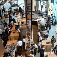 A hub of activity: Baristas pour coffee and offer drink consultations at the Starbucks Reserve Roastery Tokyo\'s first-floor main bar. | CLAIRE WILLIAMSON
