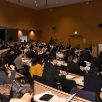 Audience members listen to a presentation by Hiroshi Aoi, president of retail chain Marui Group Co. | YOSHIAKI MIURA