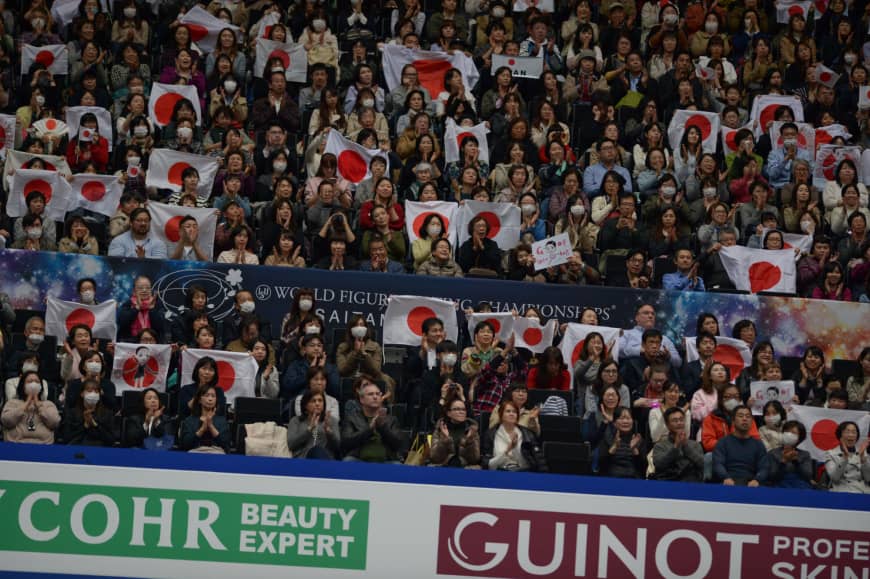 Fans hold up Japanese flags before Satoko Miyahara