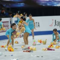 Flower girls collect Winnie the Pooh toys thrown on the ice after Yuzuru Hanyu\'s short program on Thursday in Saitama. | DAN ORLOWITZ