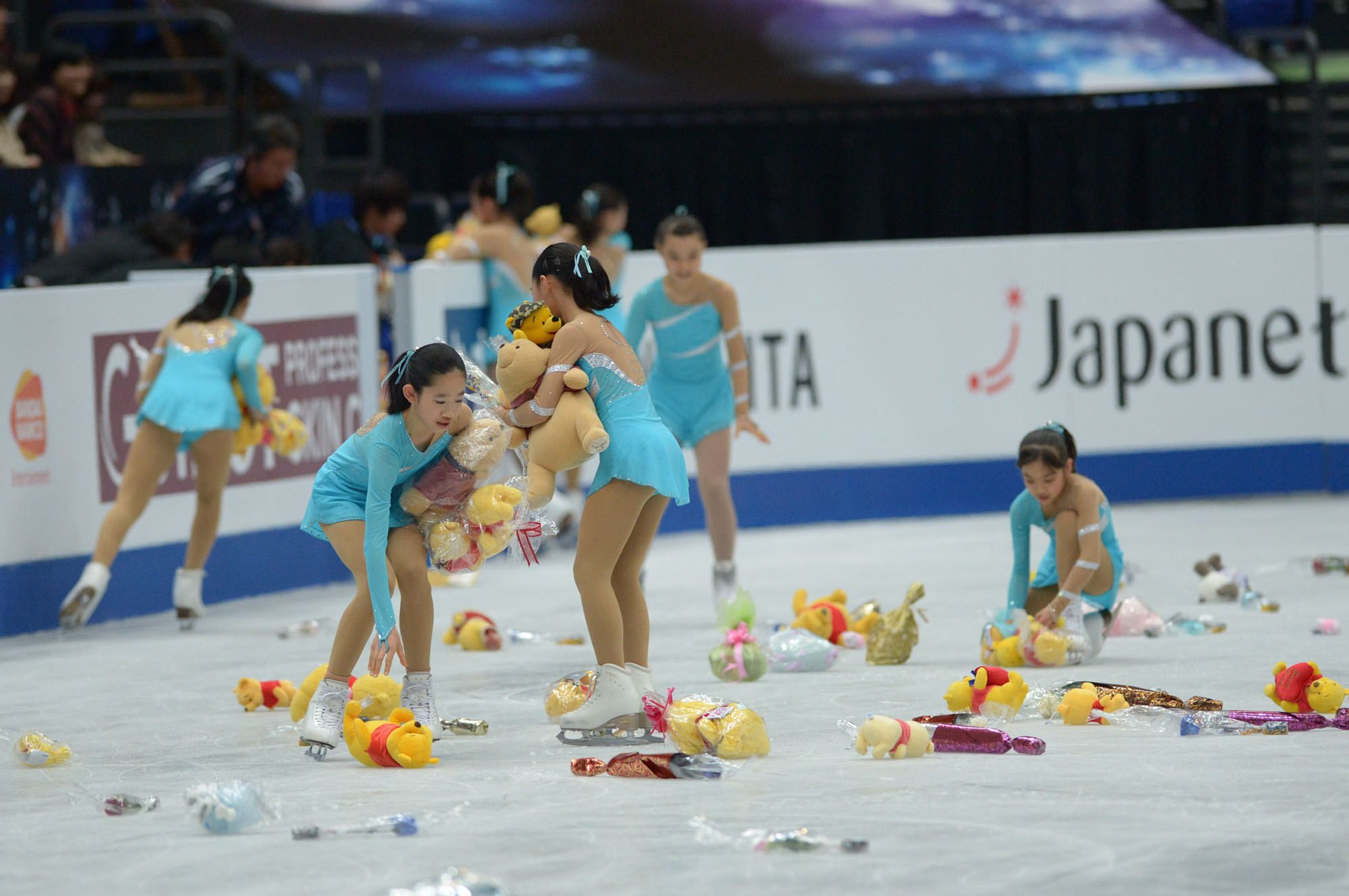 Flower girls collect Winnie the Pooh toys thrown on the ice after Yuzuru Hanyu's short program on Thursday in Saitama. | DAN ORLOWITZ