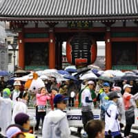 Some of the runners participating in Sunday\'s Tokyo Marathon take photographs as they pass by Sensoji Temple in the capital\'s Asakusa district. | YOSHIAKI MIURA