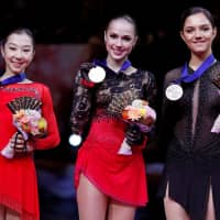 Runner-up Elizabet Tursynbaeva of Kazakhstan (left), gold medalist Alina Zagitova of Russia and third-place finisher Evgenia Medvedeva of Russia pose for photographers on the awards podium after the completion of the women\'s free skate on Friday. | REUTERS