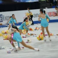 \"Flower girls\" collect stuffed animals thrown onto the ice after Yuzuru Hanyu\'s performance. | DAN ORLOWITZ