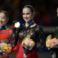 Elizabet Tursynbaeva (left), Alina Zagitova (center) and Evgenia Medvedeva pose with their world championship medals and bouquets Friday at Saitama Super Arena. | DAN ORLOWITZ
