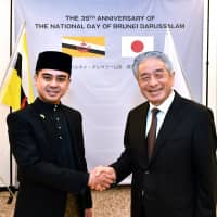 Ian Maidin, Brunei charge d\'affaires ad interim (left), shakes hands with Masataka Fujita, secretary general of the ASEAN-Japan Centre, during a reception to celebrate Brunei Darussalam\'s 35th national day at the ASEAN-Japan Centre on Feb. 28. | YOSHIAKI MIURA