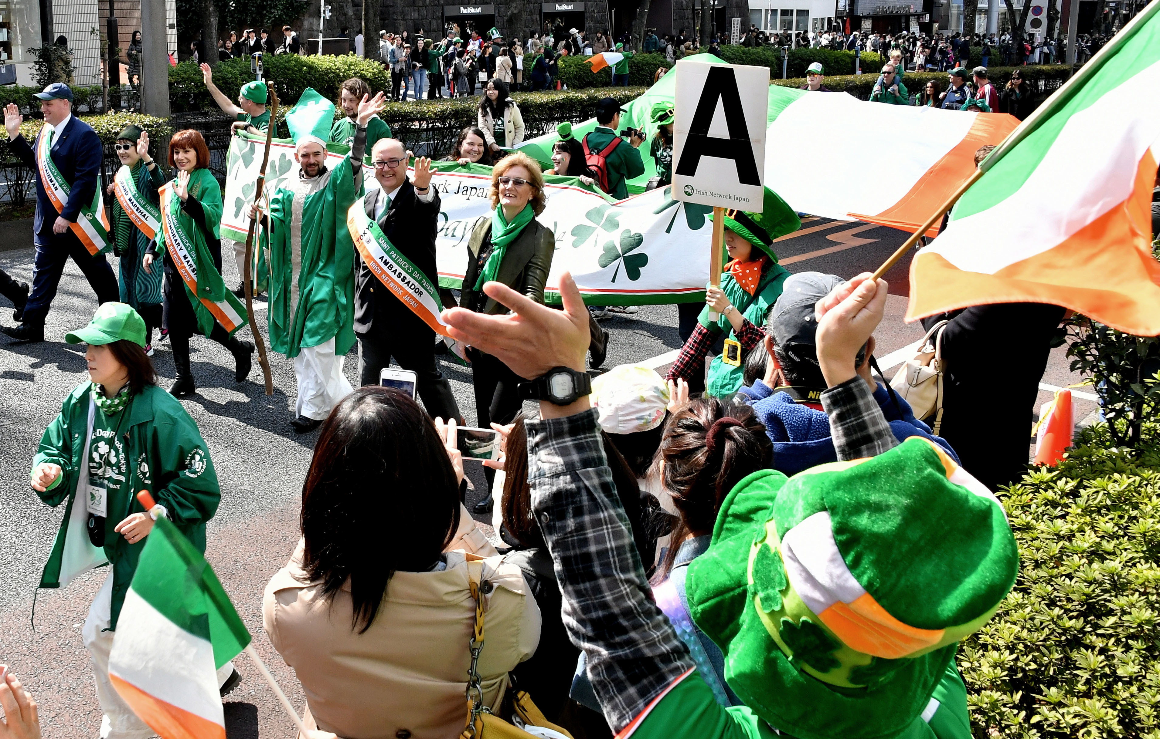 'St. Patrick' walks beside Irish Ambassador Paul Kavanagh (right) and Culture Minister Josepha Madigan in the St. Patrick's Day Parade on Omotesando-dori in Tokyo's Harajuku district on Sunday. About 1,530 people took part in the parade, which attracted 50,000 visitors. | YOSHIAKI MIURA