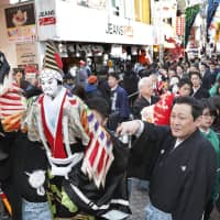 Traditional bunraku puppeteers with their puppets march along Takeshita-dori in Shibuya Ward, Tokyo, on Friday. The event was held to promote a play scheduled to be performed from Saturday to Tuesday at nearby Meiji Shrine. | KYODO