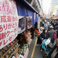 People shop Saturday next to a poster advertising a store\'s \"last coupons of the Heisei Era\" at the Ameyoko shopping district in Tokyo\'s Taito Ward. Ameyoko is running the \"Last Heisei Cherry Blossom Festival\" sales campaign until April 7. | KYODO