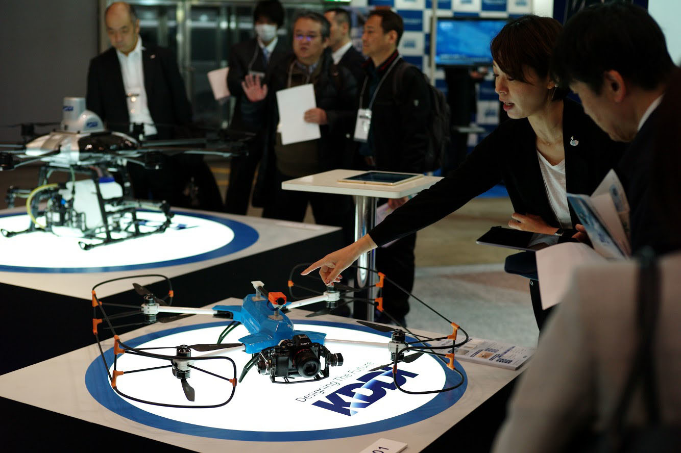 A KDDI Corp. staff member shows a drone displayed at the company's booth at the Japan Drone 2019 expo at Makuhari Messe in Chiba Prefecture on Wednesday. A total of 15,000 people are expected to visit the three-day event, which kicked off the same day. | RYUSEI TAKAHASHI