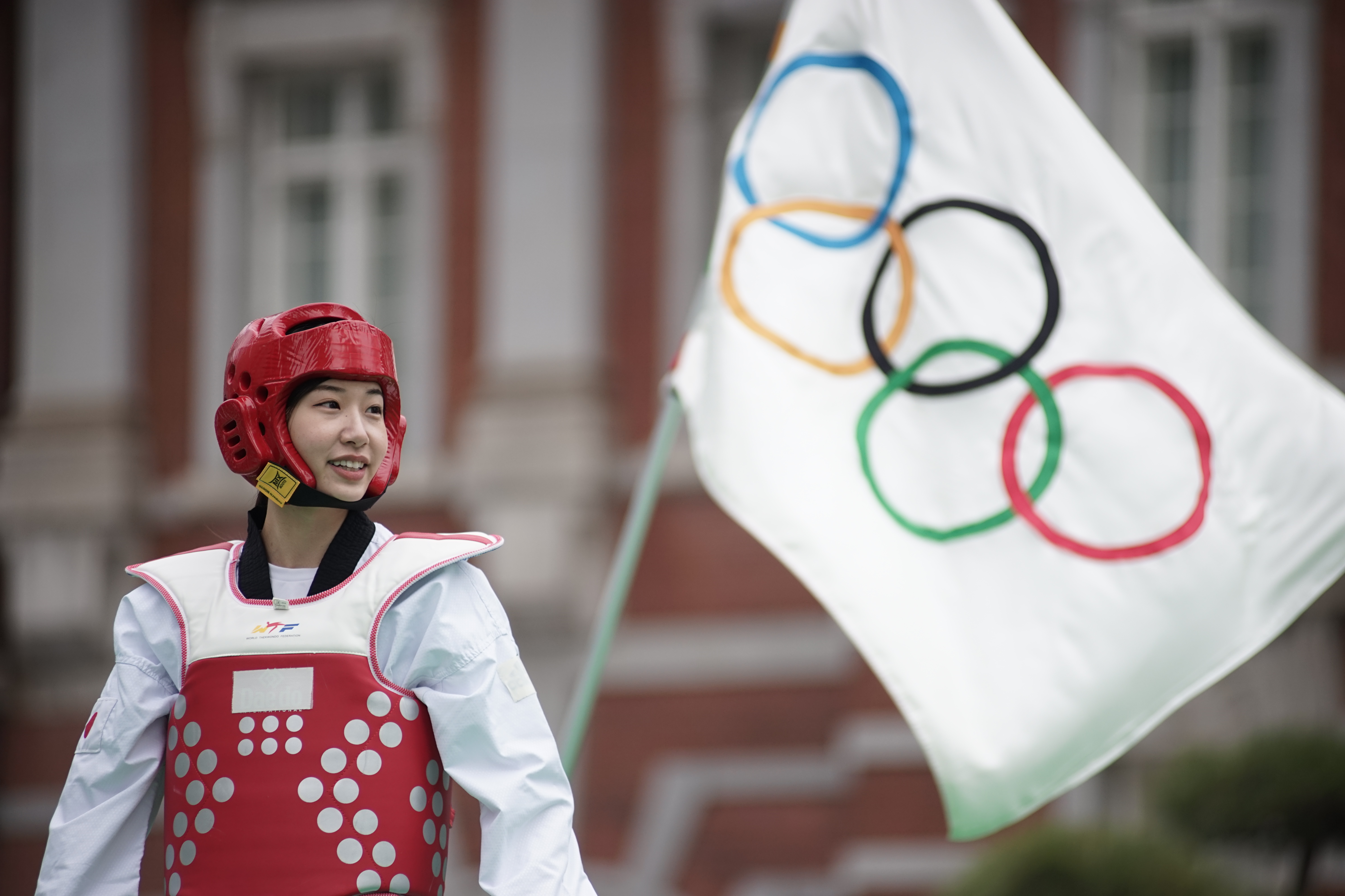 Miyu Yamada, a Japanese taekwondo competitor who won a bronze medal at the 2018 Asian Games in Jakarta, stands by one of two Olympic flags that were handed over to Tokyo from Rio de Janeiro, where the 2016 Olympic Games were held, during  an event outside Tokyo Station on Saturday. | RYUSEI TAKAHASHI