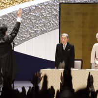 Prime Minister Shinzo Abe does a traditional \"banzai\" (long life) cheer to Emperor Akihito and Empress Michiko during  a ceremony to mark the 30th year of his reign at the National Theater in Tokyo on Feb. 24. | POOL / VIA AP