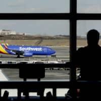 A Southwest Airlines jet taxis as a person eats at a terminal restaurant at LaGuardia Airport in New York in January. A technical outage is impacting major airlines and causing flight delays that may lead to a ripple effect throughout Monday. | AP