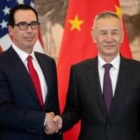 Chinese Vice Premier Liu He gestures next to U.S. Treasury Secretary Steven Mnuchin as they pose for a group photo at Diaoyutai State Guesthouse in Beijing Friday. | REUTERS