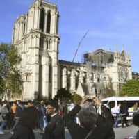 People gather in front of Notre-Dame Cathedral in Paris on Wednesday, two days after a big fire gutted part of the iconic building, a designated UNESCO World Heritage site. | KYODO