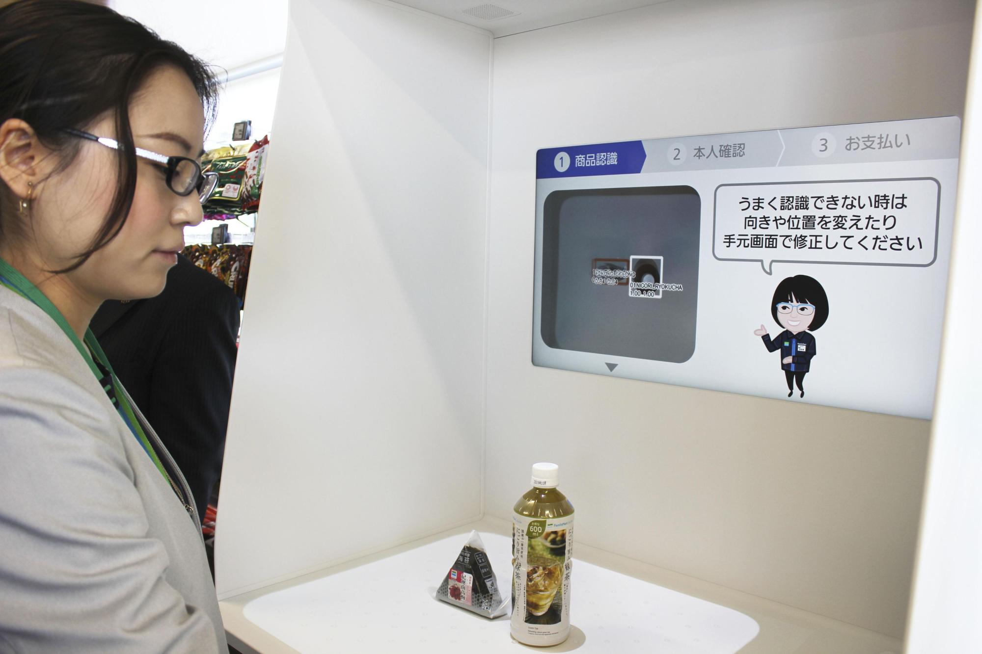 A woman demonstrates a facial recognition cashier system at a FamilyMart store in Yokohama on Tuesday. | KYODO