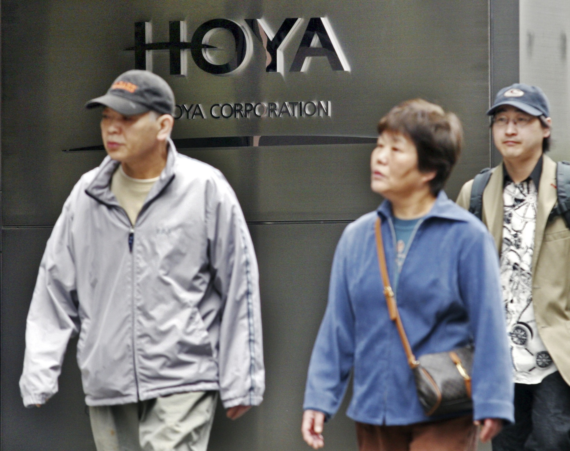 Pedestrians walk past in front of Hoya Corp. headquarters in Tokyo. The leading Japanese eyeglass lens maker was hit by a cyberattack at its key production base in Thailand in late February. | BLOOMBERG NEWS