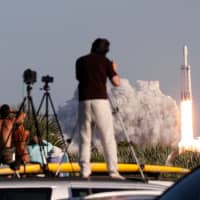 Visitors at Playalinda Beach look on as a SpaceX Falcon Heavy rocket launches from Pad 39B at the Kennedy Space Center in Florida Thursday. SpaceX\'s Falcon Heavy ferried the Arabsat-6A communications satellite into orbit for Saudi Arabia in the first commercial mission of the world\'s most powerful rocket. | AFP-JIJI