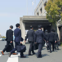 Transport ministry officials enter the headquarters of Suzuki Motor Corp. on Friday as part of an investigation into improper quality inspections related to the automaker\'s recall of more than 2 million cars in Japan. | KYODO