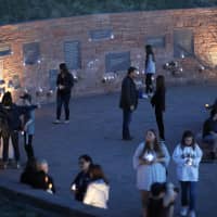 Attendees walk through the Columbine Memorial in Littleton, Colorado, during Friday\'s vigil at the site for the victims of the massacre at Columbine High School on April 20, 1999. | AP