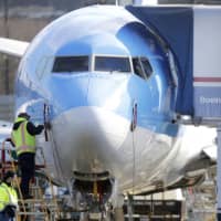 A worker stands on a platform near a Boeing 737 Max 8 airplane being built for TUI Group at Boeing Co.\'s Renton Assembly Plant in Renton, Washington, on March 13. | AP