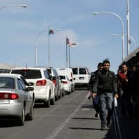 Men deported from El Paso, Texas, walk toward Ciudad Juarez at Paso del Norte international border crossing bridge, in this picture taken from Ciudad Juarez, Mexico, Tuesday. | REUTERS