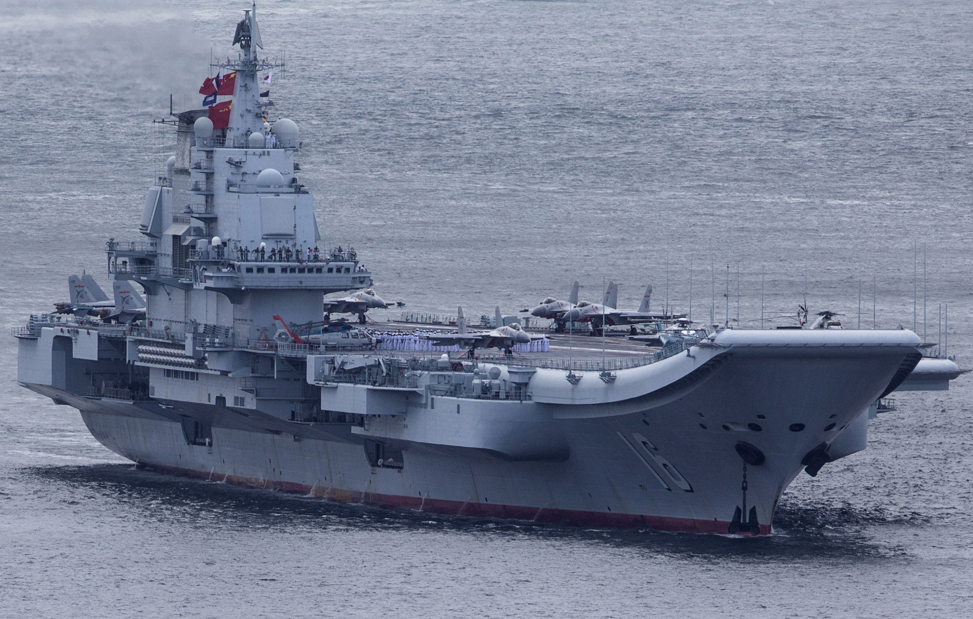 Chinese People's Liberation Army Navy personnel line the deck of the Liaoning aircraft carrier as it sails into Hong Kong in July 2017. The carrier will take part in a massive naval parade marking the 70th anniversary of China's navy on Tuesday. | BLOOMBERG