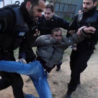 Police officers carry a migrant during scuffles as migrants and refugees, who say that they seek to travel onward to Northern Europe, gather outside a camp in the town of Diavata in northern Greece Thursday. | REUTERS