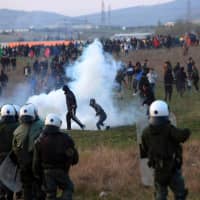 Riot police clash with migrants outside of a refugee camp in Diavata, a west suburb of Thessaloniki, Greece, on Thursday. Hundreds of migrants and refugees gathered following anonymous social media calls to walk until the northern borders of Greece to pass to Europe. | AFP-JIJI