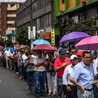 Supporters of the late Peruvian ex-President Alan Garcia waite to pay respects during his wake outside the American Popular Revolutionary Alliance (APRA) party headquarters in Lima Thursday. Garcia, who was president from 1985-90 and again from 2006-11, died in a hospital on Wednesday after shooting himself in the head at his home as police were about to arrest him over the graft investigation. | AFP-JIJI