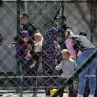 Police officers guard women and children who are relatives of Kosovo Jihadis who returned from Syria, at the foreigner detention center in Pristina Saturday. | REUTERS