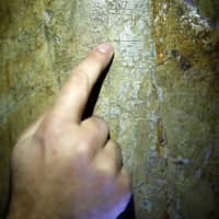 A researcher points at marks of crosses left by pilgrims on a pillar in the Cenacle, a hall revered by Christians as the site of Jesus\' Last Supper, in Mount Zion near Jerusalem\'s Old City March 14. | REUTERS