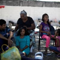A family from Honduras sits near their tents at an improvised shelter while waiting for a humanitarian visa to cross the country on their way to the United States, in Mapastepec, Chiapas state, Mexico, Sunday. | REUTERS
