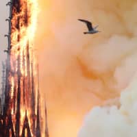 Smoke billows as fire engulfs the spire of Notre Dame Cathedral in Paris on Monday. | REUTERS