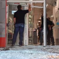 Employees are pictured inside a bank branch shortly after military police busted a gang trying to blow up ATM machines and shot dead at least 10 robbers, in Guararema, some 80 km from Sao Paulo Thursday. | AFP-JIJI