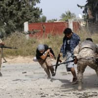 Libyan fighters loyal to the Government of National Accord (GNA) run as they fire their guns during clashes with forces loyal to strongman Khalifa Hifter south of the capital Tripoli\'s suburb of Ain Zara, on Saturday. | AFP-JIJI