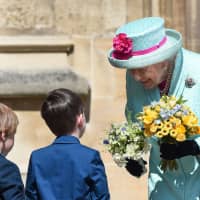 Queen Elizabeth II smiles after she received posies of flowers from children after attending the Easter Mattins Service at St. George\'s Chapel at Windsor Castle, west of London, on Sunday. | AFP-JIJI