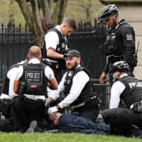 Police and rescue personnel tend to a man in Lafayette Park in Washington after the man lit his jacket on fire in front of the White House on Friday. | REUTERS