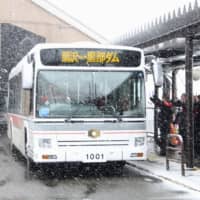 An electric bus departs from Ogisawa Station in Omachi, Nagano Prefecture, on Monday as the Tateyama Kurobe Alpine Route, which features massive snow walls, opened for this year\'s tourist season. | KYODO