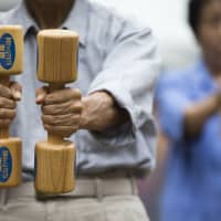 People exercise with wooden dumbbells during an event marking Respect for the Aged Day at a temple in the Sugamo district of Tokyo in September 2016. A new report has said that a quarter of Japan\'s breadwinners will turn 75 or older by 2040. | BLOOMBERG