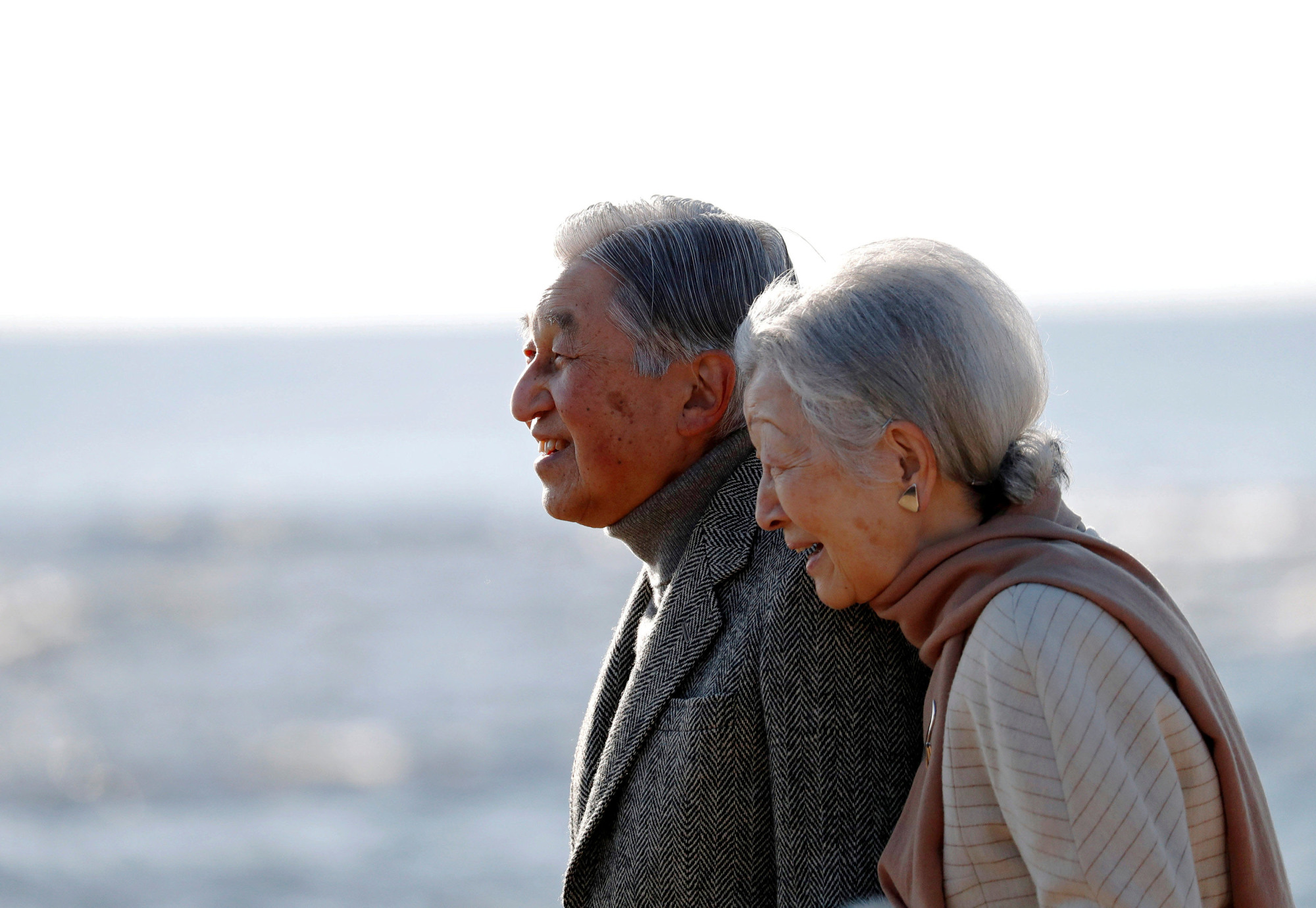 Emperor Akihito and Empress Michiko stroll on a beach near their Imperial villa, where they were staying for the Emperor's recuperation, in Hayama, Kanagawa Prefecture, on Jan. 21. | REUTERS
