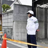 A police officer stands near a residential area in Yokohama where a man snatched a gun from another officer and fired it. No one was injured. | KYODO