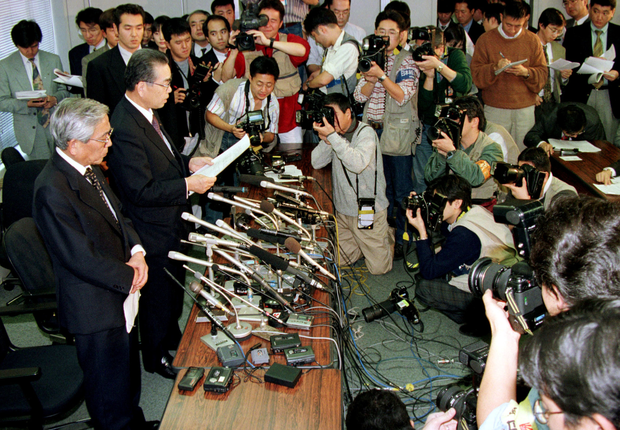 Yamaichi Securities President Shohei Nozawa (right) and Chairman Masaharu Saotome are surrounded by the media during an announcement at the Tokyo Stock Exchange on Nov. 24, 1997. | REUTERS