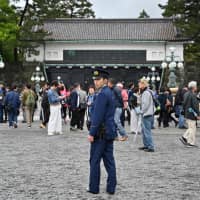 A policeman stands guard as people gather outside the Imperial Palace in Tokyo on Tuesday. | AFP-JIJI