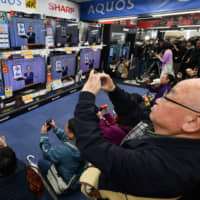 People watch TVs at an electronics store in Tokyo\'s Yurakucho district Monday as the new Imperial era name, Reiwa, is unveiled by Chief Cabinet Secretary Yoshihide Suga at a televised news conference.  | YOSHIAKI MIURA 
