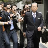 Takayoshi Yamaguchi, the former chairman of now-bankrupt Japan Life Co., is surrounded by reporters outside his house in Tokyo on Thursday. | KYODO