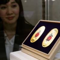 A set of pure gold coins with the current era name, Heisei (left), and the upcoming era name, Reiwa, go on sale for &#165;1,296,000 at the Takashimaya department store chain\'s Nihonbashi branch in Tokyo on Thursday. | KYODO
