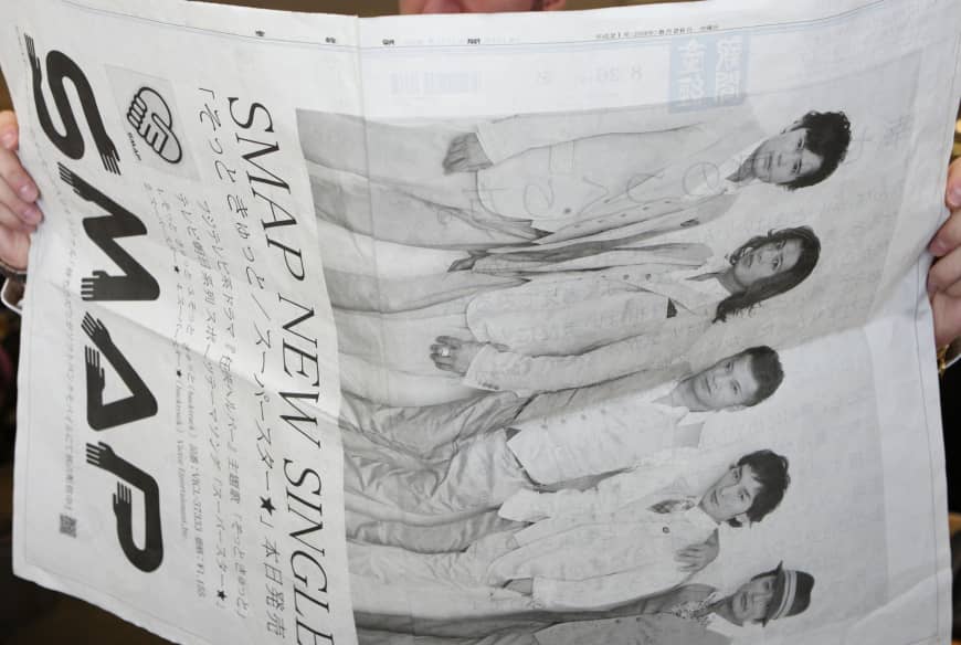 A man reads a four-page newspaper ad for SMAP in Tokyo in August 2009.